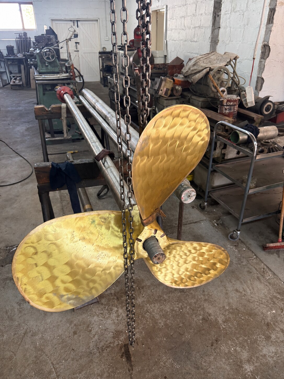 Marine propeller handled by chain block during workshop fitting
